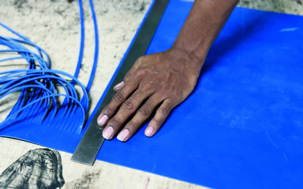 A hand and ruler measuring recycled tire innertubes, from Breaking Boundaries and Subverting Stereotypes