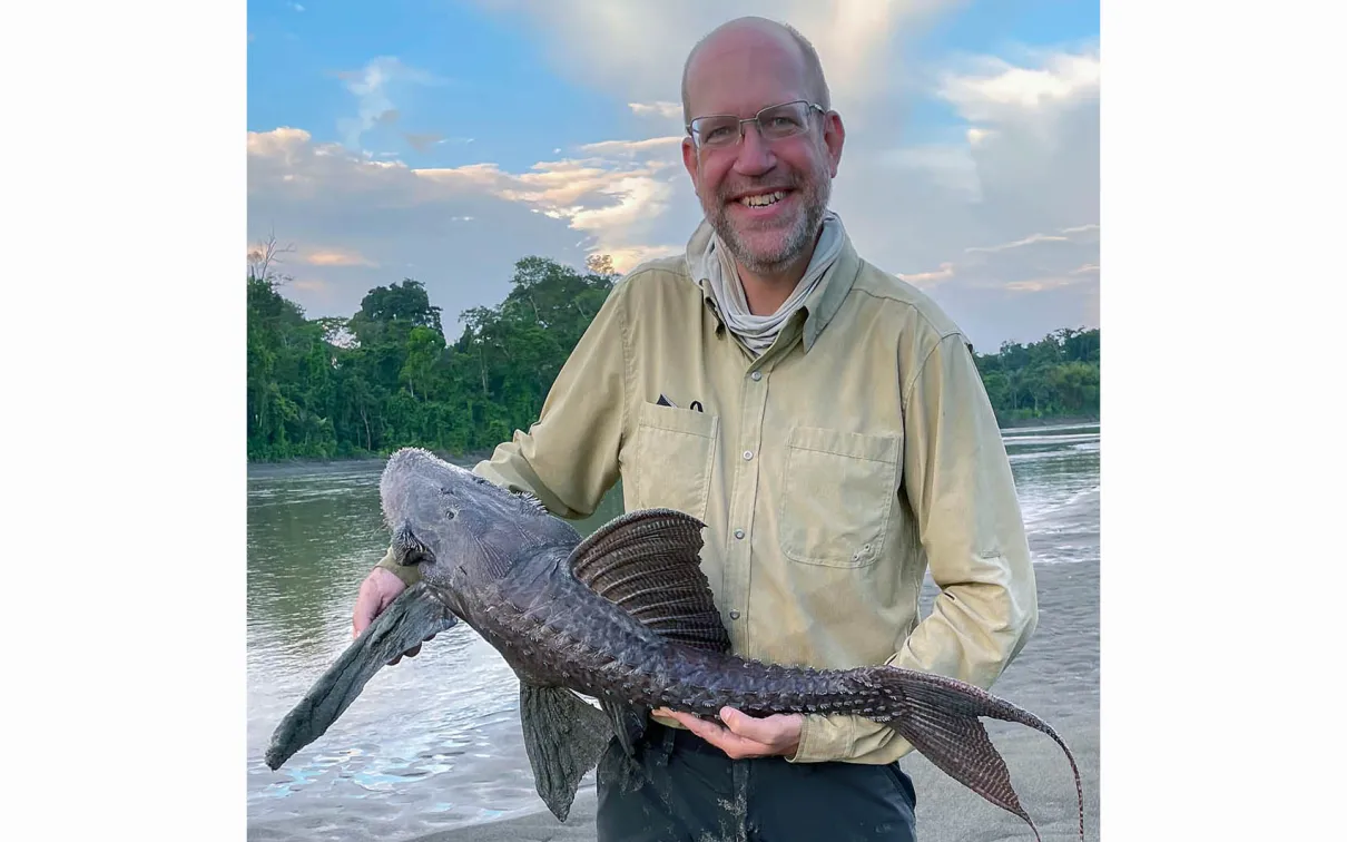 A man holding up a suckermouth armored catfish.