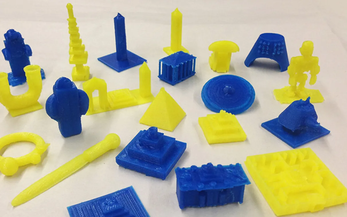 Twenty one blue and yellow 3D printed objects that include pyramids and obelisks
