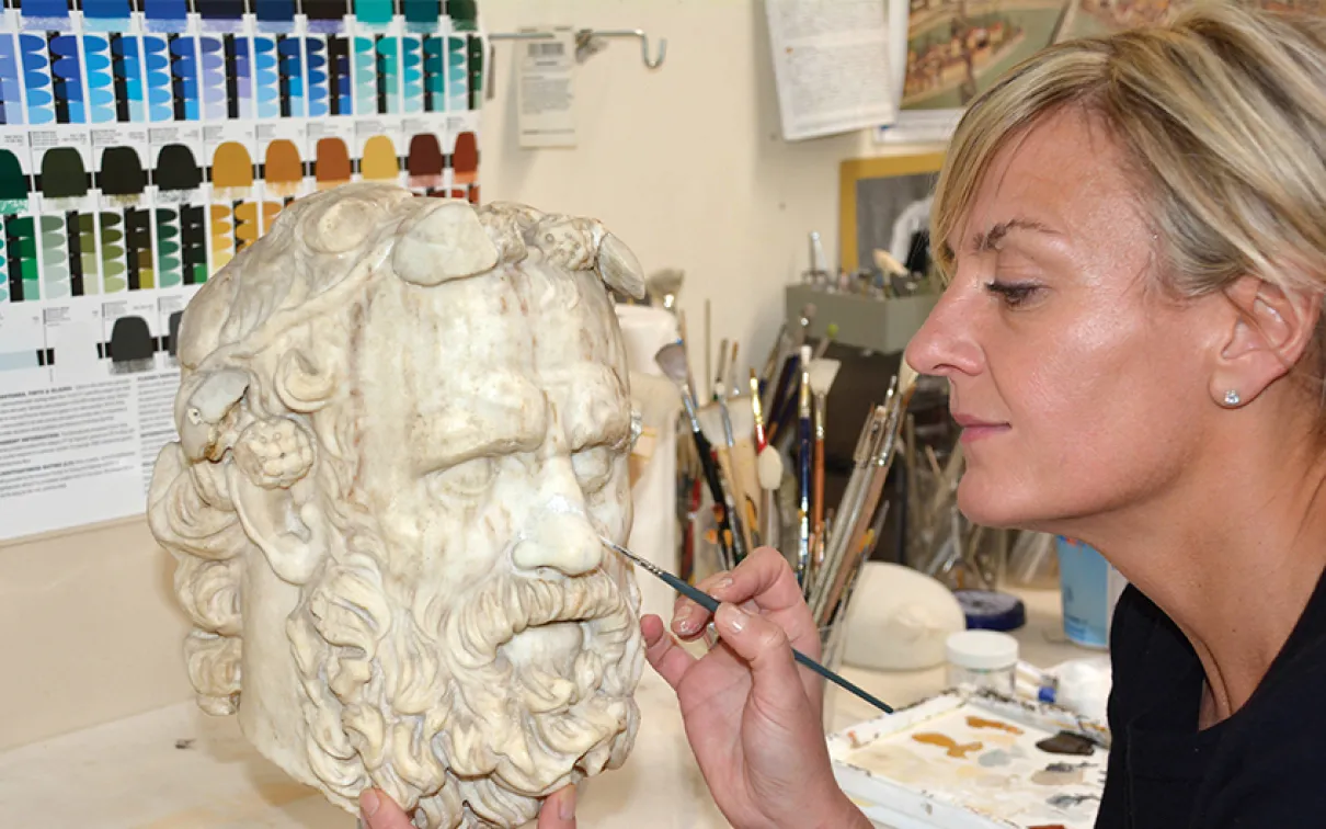 Laura Lipcei painting a Greek statue.