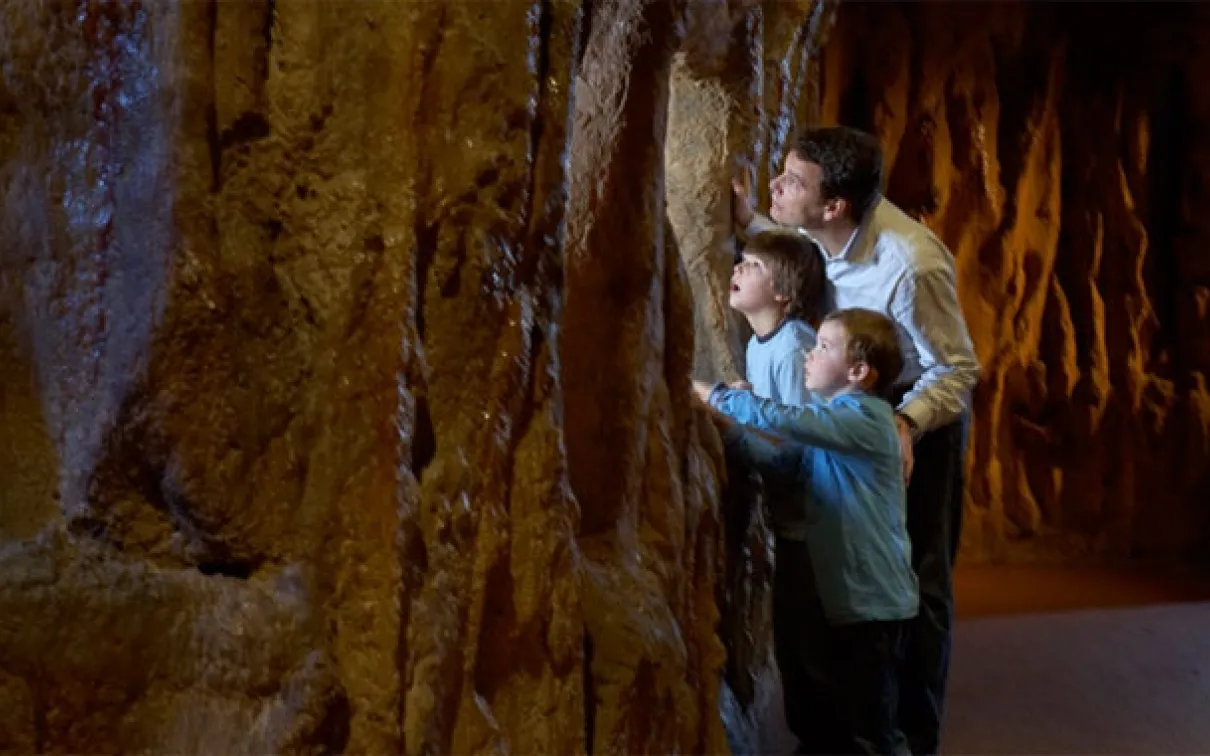 A man and two children exploring ROM's bat cave