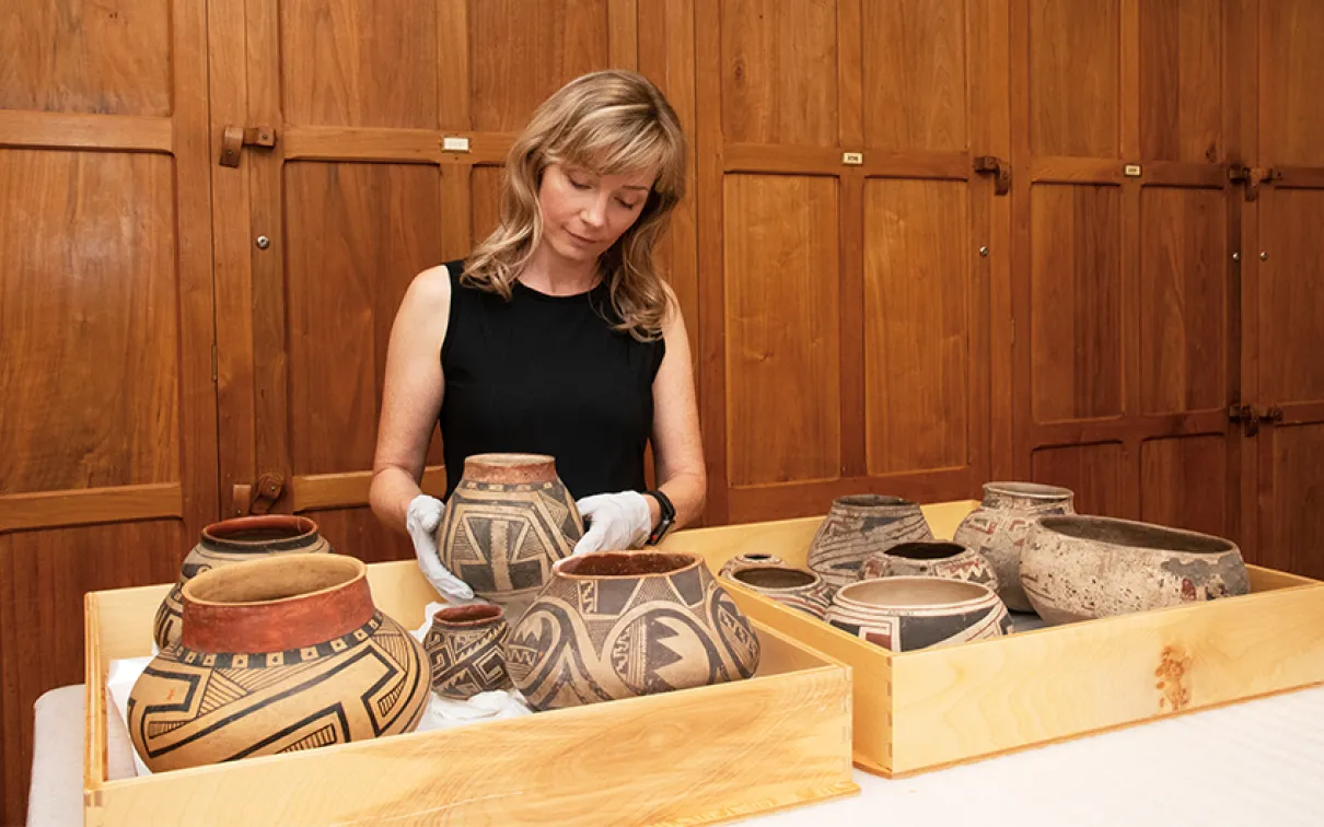 Museum technician in a collections room with artifacts.