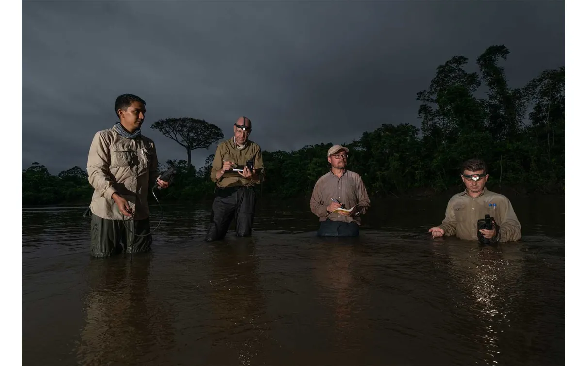 With a great Ceiba tree behind them, Lujan and Montoya's team collects water samples from a river in the Amazon. 