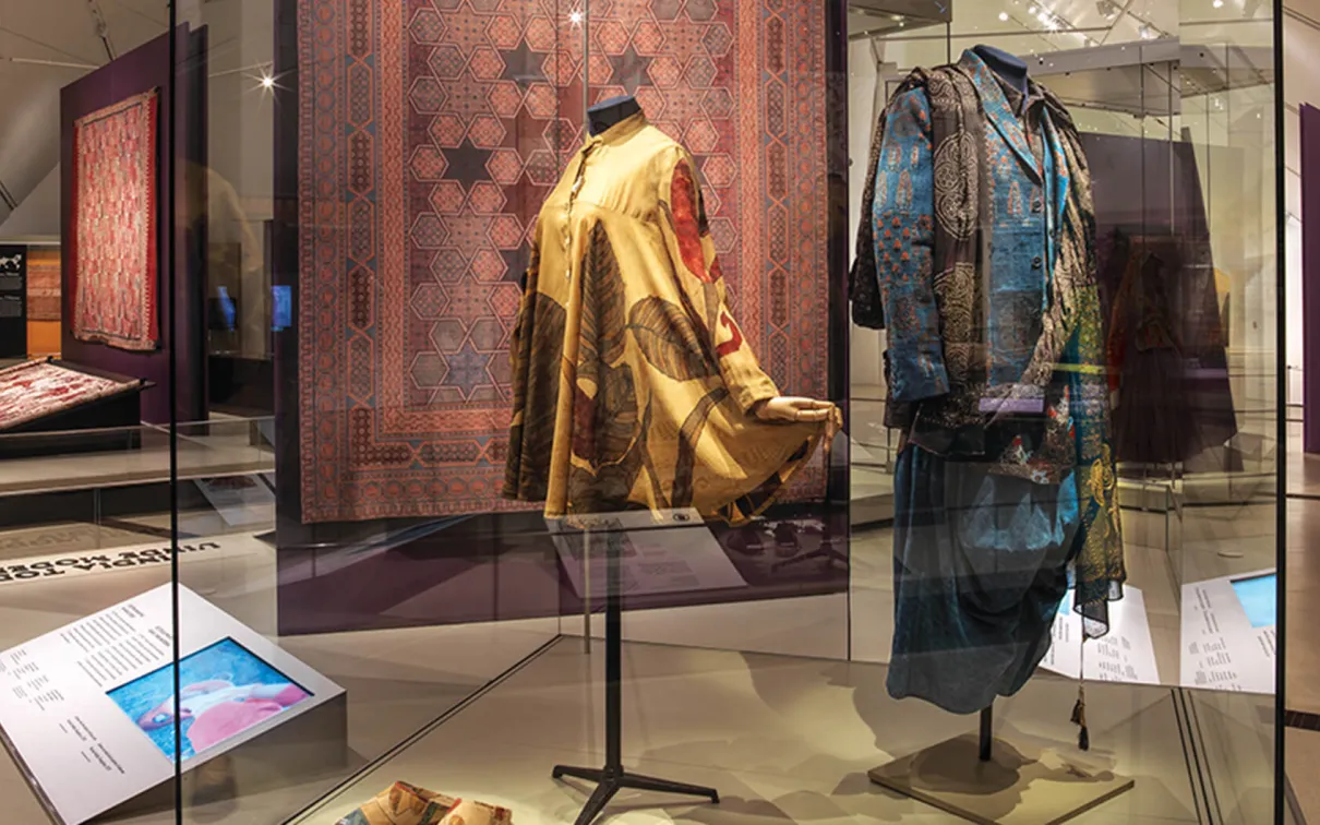 Woman’s tunic and shoes beside menswear Sindhu line in exhibition case.