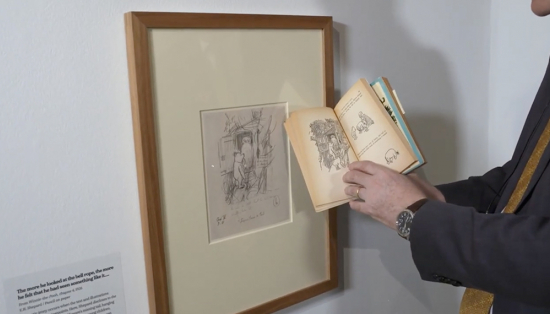 Julius Bryant holding Winnie-the-Pooh book in front of framed illustration.