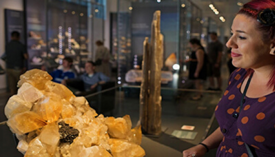 Woman looking at a mineral in a display case.