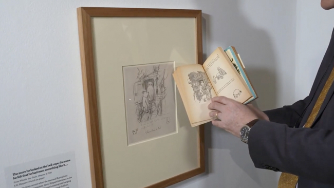 Julius Bryant holding Winnie-the-Pooh book in front of framed illustration.