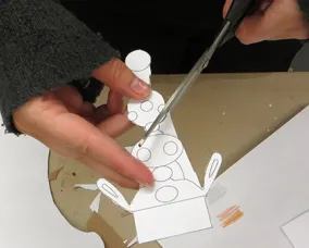 hands cut out the ornament on the template