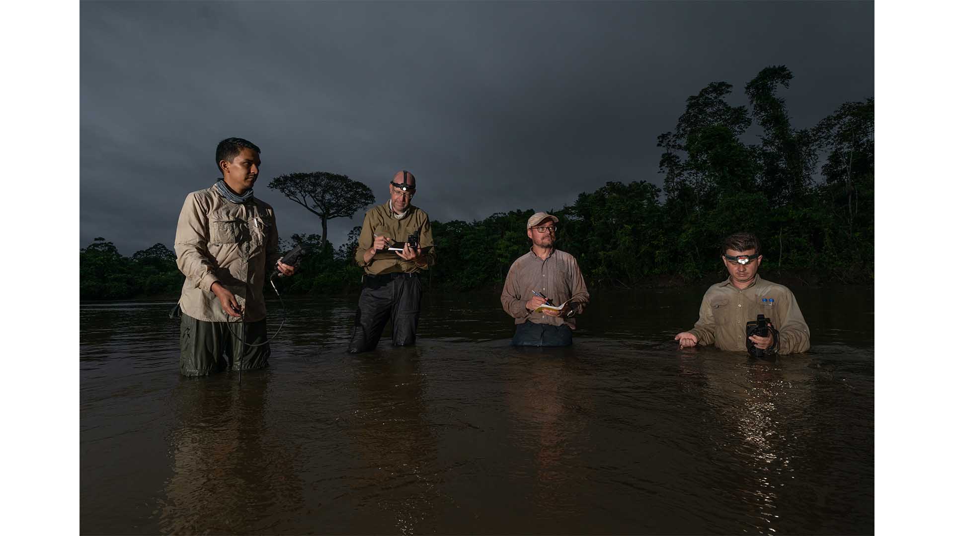 With a great Ceiba tree behind them, Lujan and Montoya's team collects water samples from a river in the Amazon. 