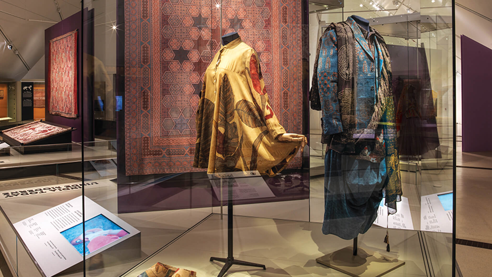 Woman’s tunic and shoes beside menswear Sindhu line in exhibition case.